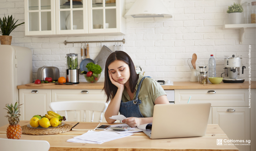 Young renter calculating monthly expenses at home to understand the true cost of renting a cheap room in Singapore.